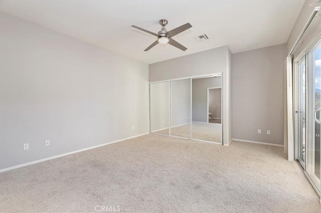 unfurnished bedroom featuring baseboards, visible vents, a ceiling fan, light colored carpet, and a closet