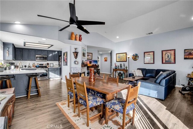 dining area with ceiling fan, vaulted ceiling, and dark hardwood / wood-style flooring