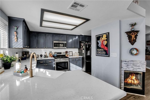 kitchen with gray cabinets, stainless steel appliances, dark wood-type flooring, a fireplace, and sink