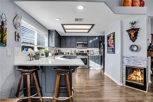 kitchen with kitchen peninsula, sink, dark wood-type flooring, appliances with stainless steel finishes, and a breakfast bar area