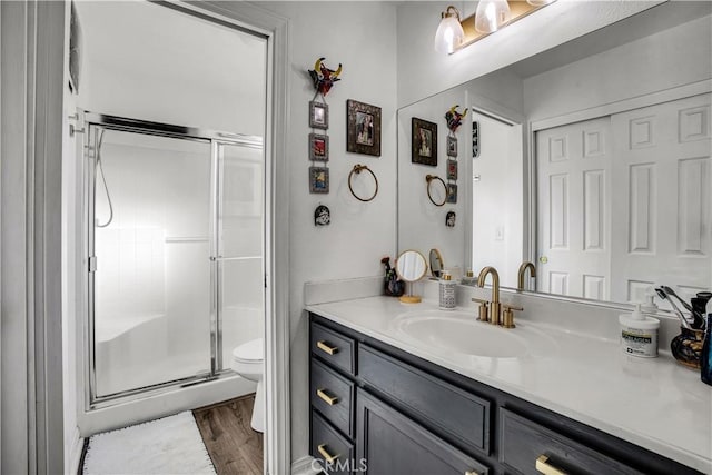 bathroom featuring hardwood / wood-style flooring, toilet, a shower with door, and vanity