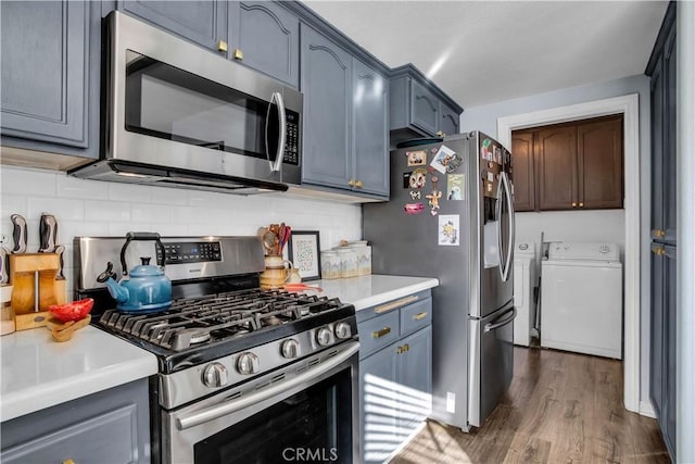 kitchen featuring dark wood-type flooring, separate washer and dryer, decorative backsplash, and appliances with stainless steel finishes