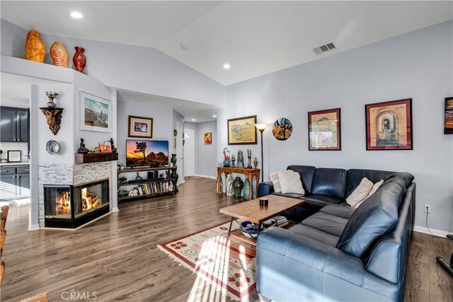 living room featuring lofted ceiling, dark wood-type flooring, and a multi sided fireplace