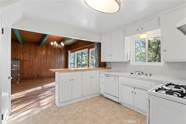 kitchen with white appliances, beam ceiling, a sink, wood walls, and a wealth of natural light