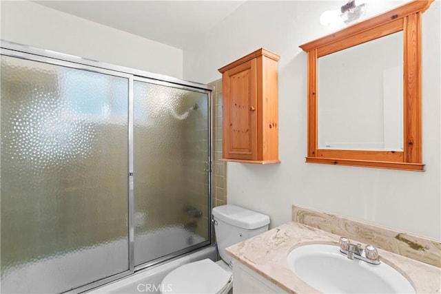 bathroom with combined bath / shower with glass door, toilet, and vanity