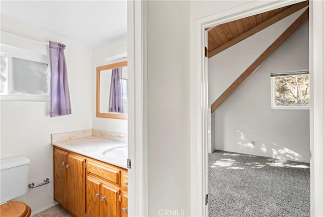 half bath with lofted ceiling, toilet, and vanity