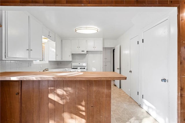 kitchen featuring a peninsula, white cabinets, white range with gas stovetop, and under cabinet range hood