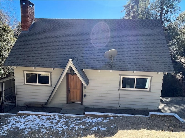 view of front of home with roof with shingles and a chimney