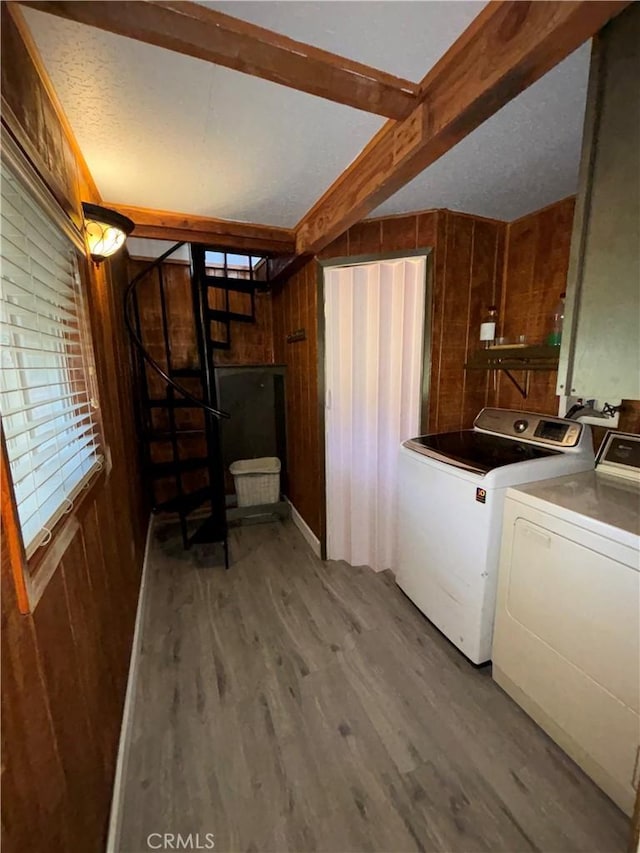 washroom with wood walls, separate washer and dryer, a textured ceiling, and hardwood / wood-style flooring