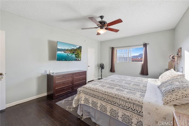 bedroom with ceiling fan, dark hardwood / wood-style flooring, and a textured ceiling