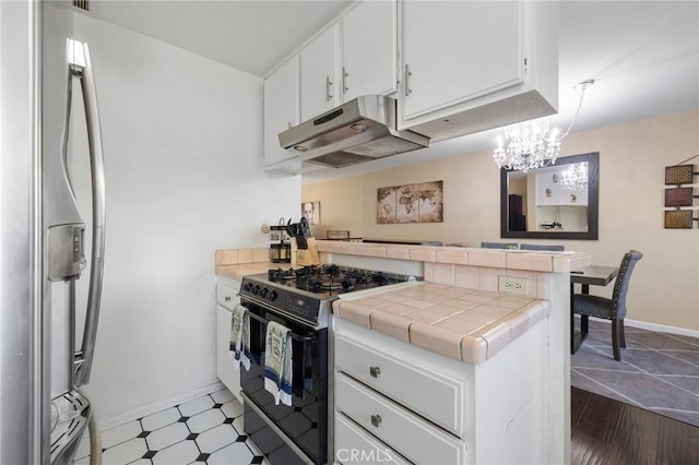 kitchen with tile countertops, black range with gas stovetop, kitchen peninsula, stainless steel refrigerator with ice dispenser, and white cabinetry