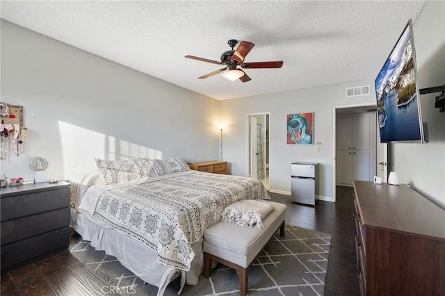 bedroom featuring ceiling fan, dark hardwood / wood-style floors, stainless steel refrigerator, a textured ceiling, and a closet