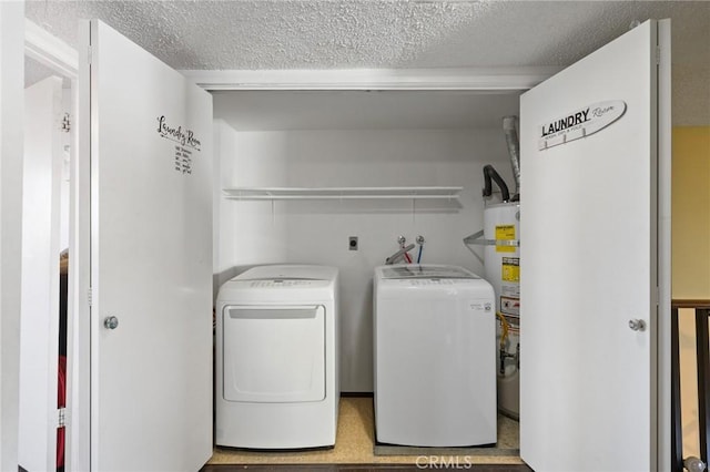 washroom featuring washing machine and dryer, a textured ceiling, and water heater