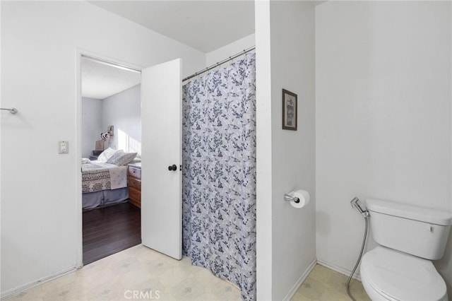 bathroom with toilet and a shower with shower curtain