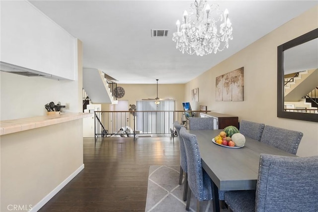 dining space featuring dark hardwood / wood-style flooring and ceiling fan with notable chandelier