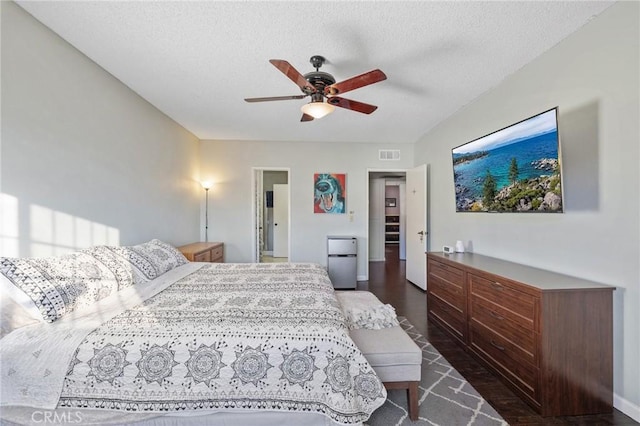 bedroom with a textured ceiling, ceiling fan, and stainless steel fridge