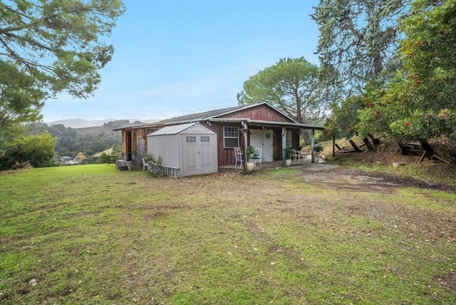 back of house with a mountain view, a yard, and a shed