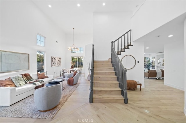 stairs with hardwood / wood-style flooring, a high ceiling, and a chandelier