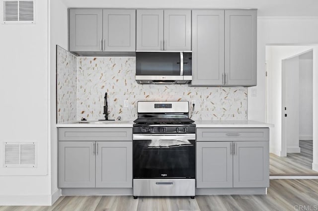 kitchen featuring stainless steel appliances, sink, gray cabinets, and light hardwood / wood-style flooring