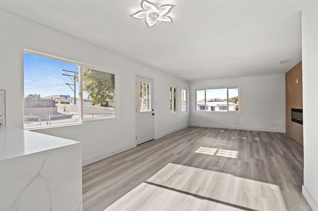 unfurnished living room featuring wooden walls and light wood-type flooring