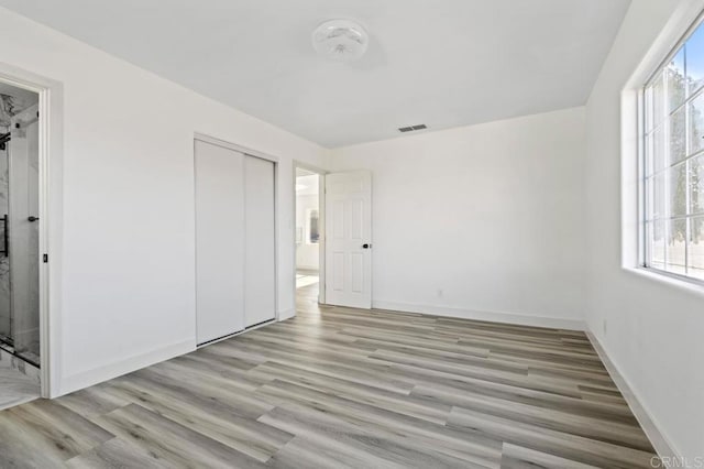 unfurnished bedroom with light wood-type flooring and a closet