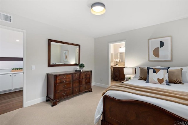 bedroom with light carpet, connected bathroom, visible vents, and baseboards