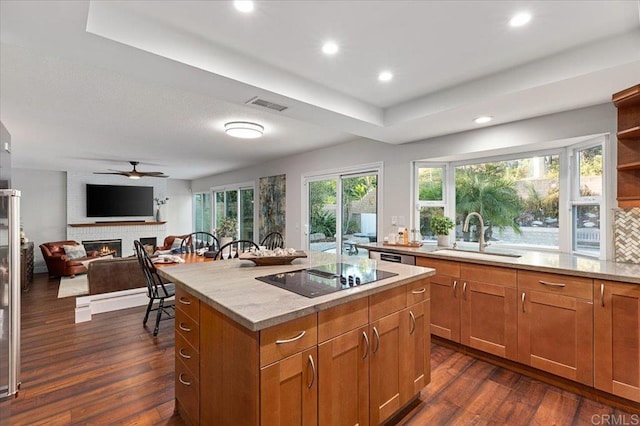 kitchen with dark wood-style floors, a fireplace, black electric cooktop, and a sink