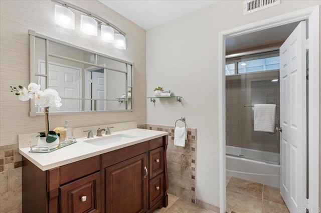 bathroom with enclosed tub / shower combo, tile patterned flooring, visible vents, vanity, and tile walls