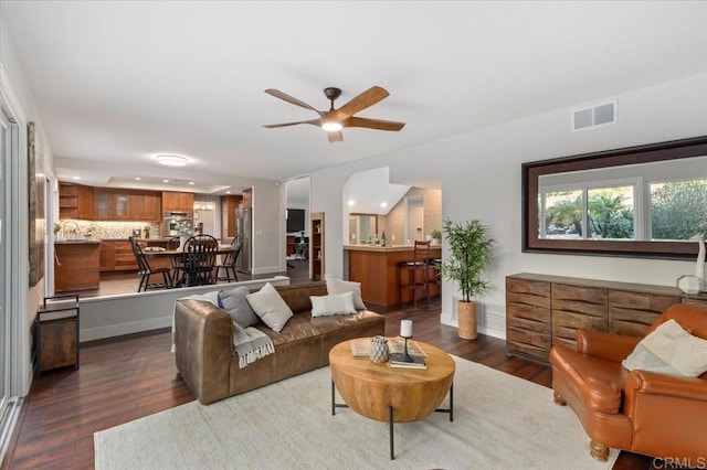 living area featuring baseboards, dark wood-style flooring, visible vents, and a ceiling fan