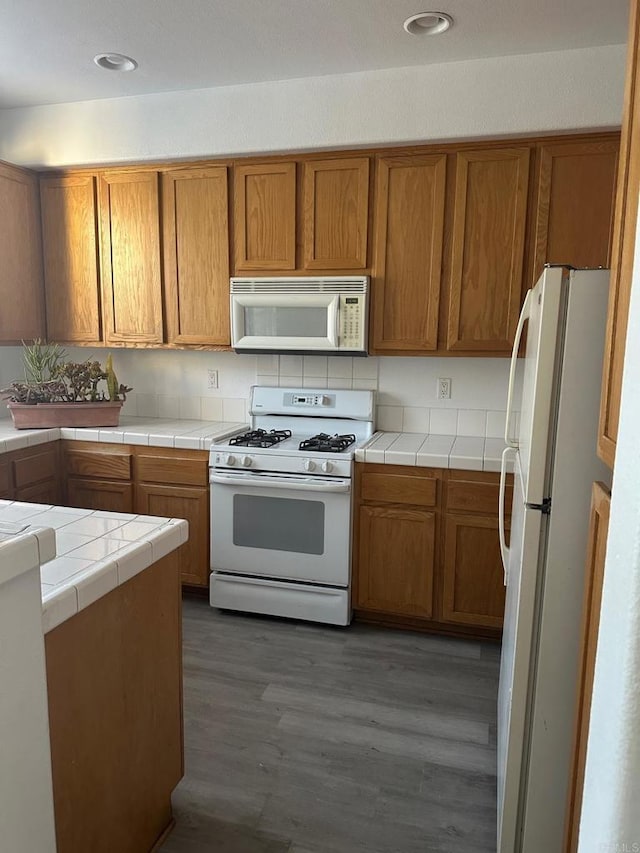 kitchen with tile counters, dark hardwood / wood-style floors, and white appliances