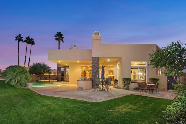 back of property with a patio, a lawn, and stucco siding