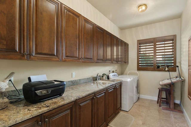 clothes washing area with washer and clothes dryer, light tile patterned floors, cabinet space, a sink, and baseboards