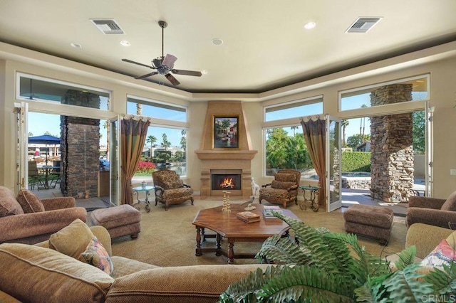 carpeted living room with a large fireplace, visible vents, and a wealth of natural light