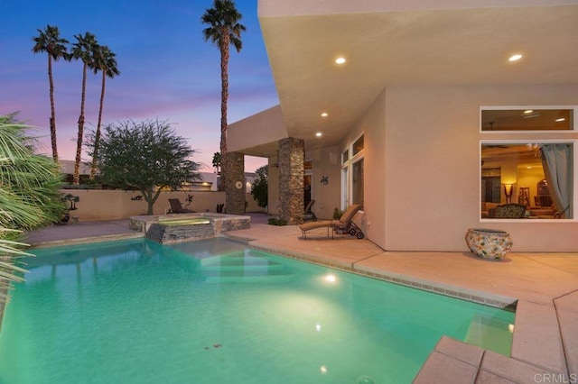 view of swimming pool with a patio area, fence, and a pool with connected hot tub