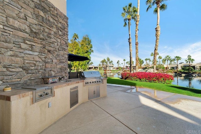 view of patio / terrace with area for grilling, grilling area, a sink, and a water view