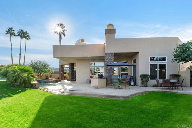 rear view of house featuring stucco siding, a lawn, and a patio