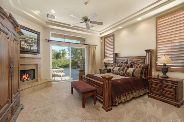 bedroom featuring light colored carpet, a raised ceiling, visible vents, and access to exterior