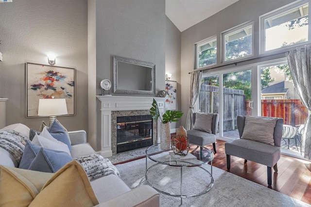 living room with a premium fireplace, high vaulted ceiling, and hardwood / wood-style floors