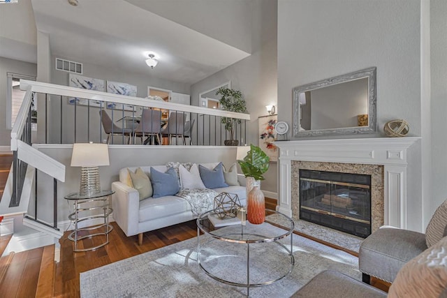 living room with a high end fireplace and dark wood-type flooring