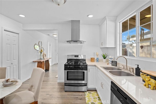 kitchen featuring white cabinets, wall chimney range hood, stainless steel appliances, sink, and light hardwood / wood-style flooring