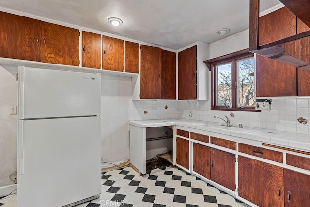 kitchen with decorative backsplash, sink, tile countertops, and white fridge