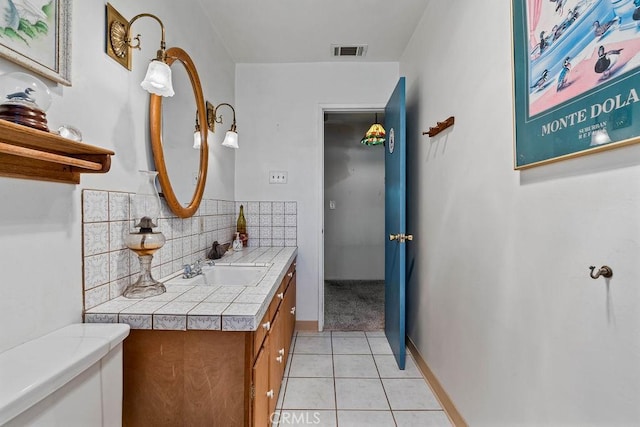 bathroom featuring toilet, tile patterned floors, backsplash, and vanity