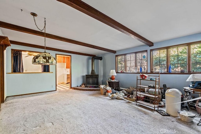 living room with a wood stove, beam ceiling, and carpet floors