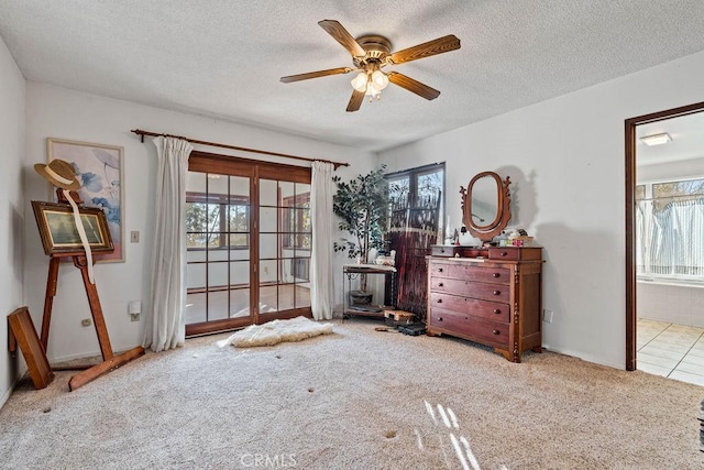 bedroom featuring ensuite bath, light colored carpet, ceiling fan, and a textured ceiling