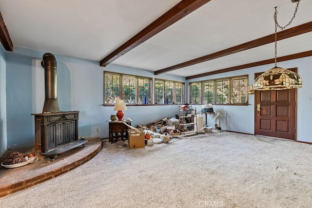 carpeted living room featuring a wood stove and beam ceiling