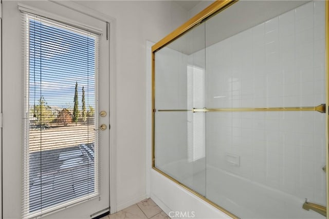 bathroom featuring a wealth of natural light and shower / bath combination with glass door