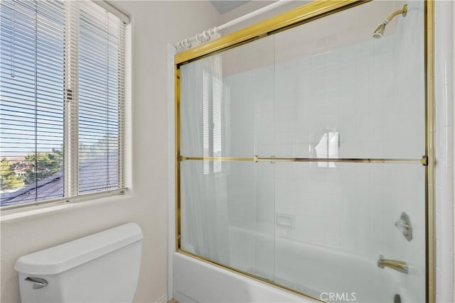 bathroom with toilet and bath / shower combo with glass door