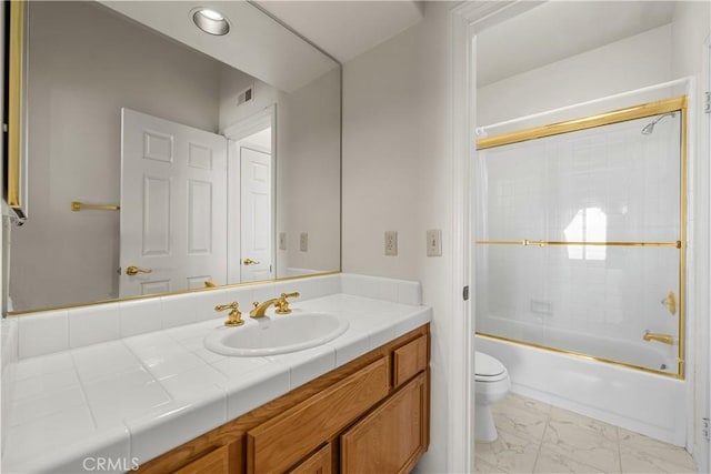 full bathroom featuring toilet, vanity, and combined bath / shower with glass door