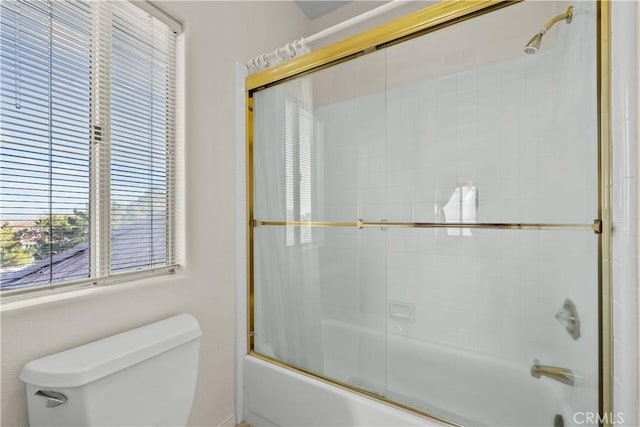 bathroom with toilet and combined bath / shower with glass door