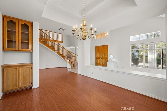 interior space featuring hardwood / wood-style flooring, a raised ceiling, and an inviting chandelier